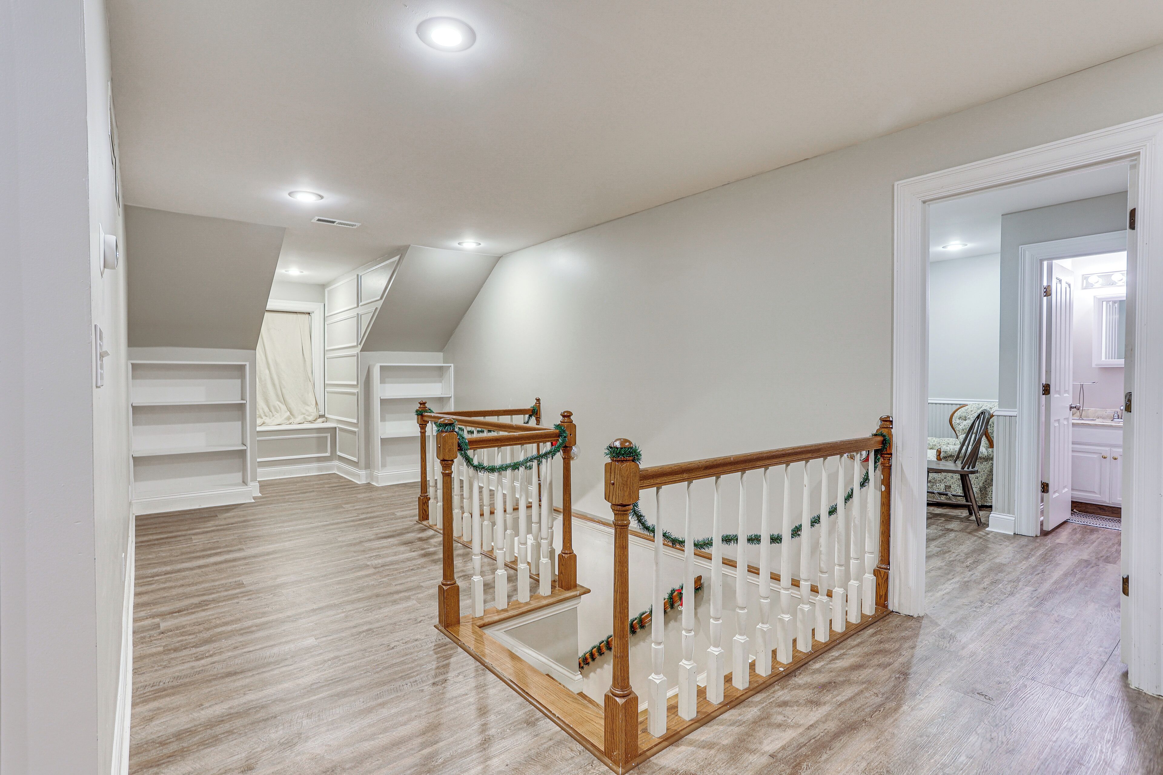 Ein geräumiges Zimmer mit einer Holztreppe, weißen Wänden und einem hellen Holzboden.