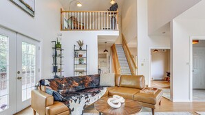 A spacious living room with a sectional sofa, a coffee table, and a staircase leading to an upper level. - Secluded Kerhonkson Retreat With Deck + Views! (Kerhonkson)
