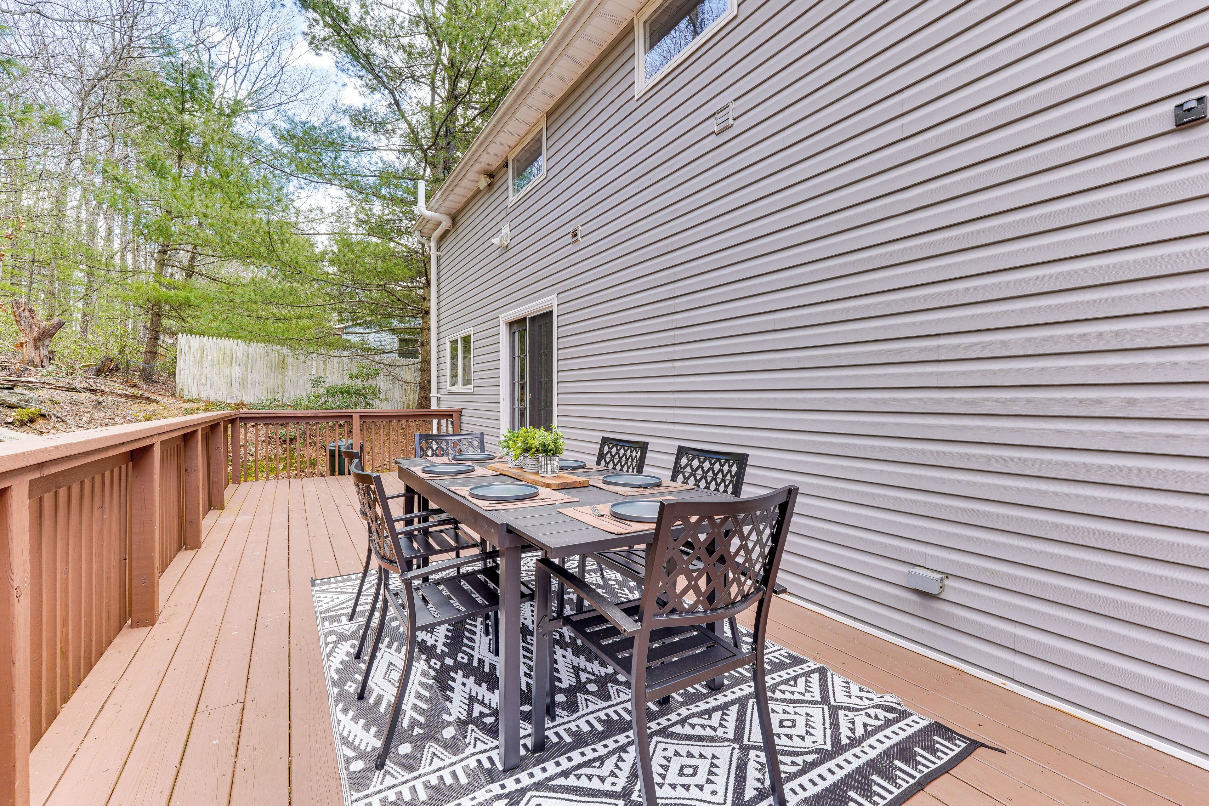 A deck with a dining table and chairs, a wooden fence, and a house with siding.