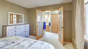 Un dormitorio con cama, cómoda y dos puertas que dan a otras habitaciones.