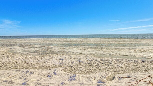 Una playa con cielo despejado y mar tranquilo.