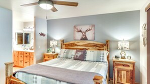 Ein Schlafzimmer mit einem Holzbett, Deckenventilator, einem Hirschbild an der Wand, Nachttischlampen und einem Nachttisch aus Holz.