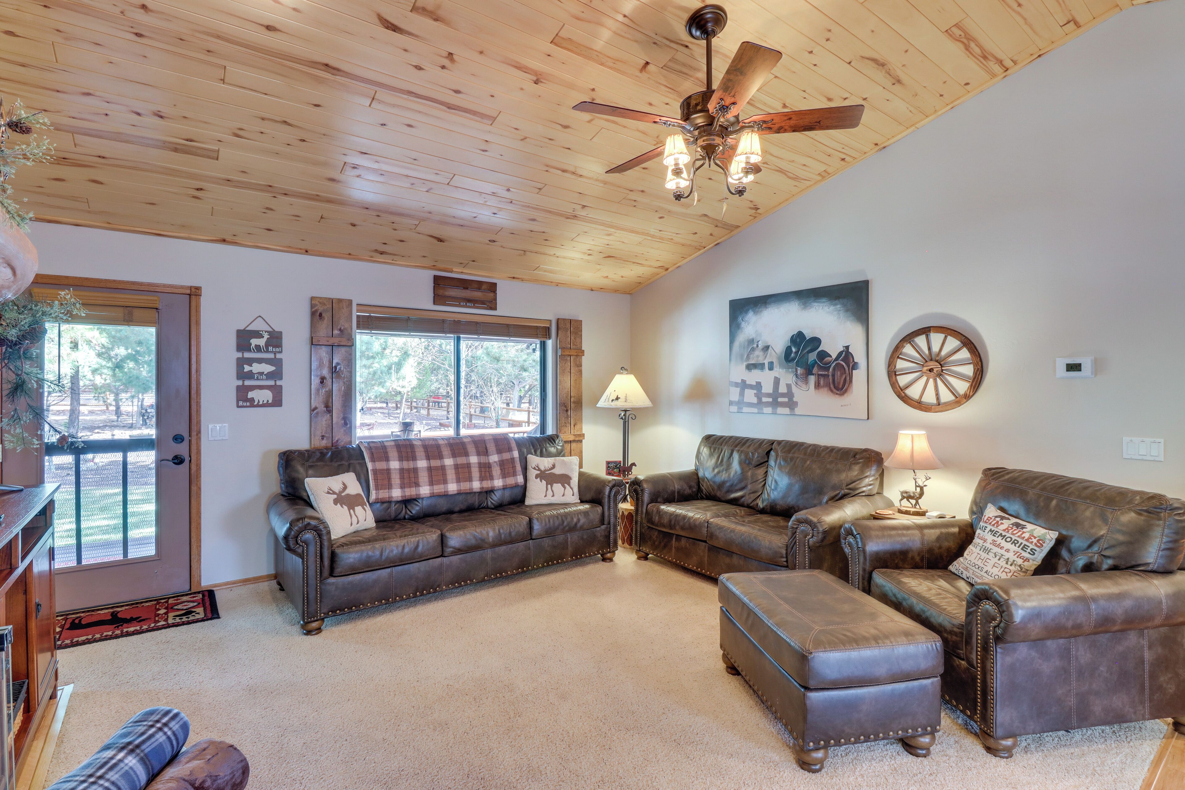 A cozy living room with leather sofas, a wooden ceiling, and a large window.