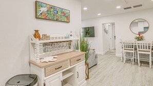 A modern kitchen with white cabinetry, a wooden countertop, and a dining area with a white table and chairs. - Heated Pool + Backyard: North Palm Beach Retreat! (Juno Beach)