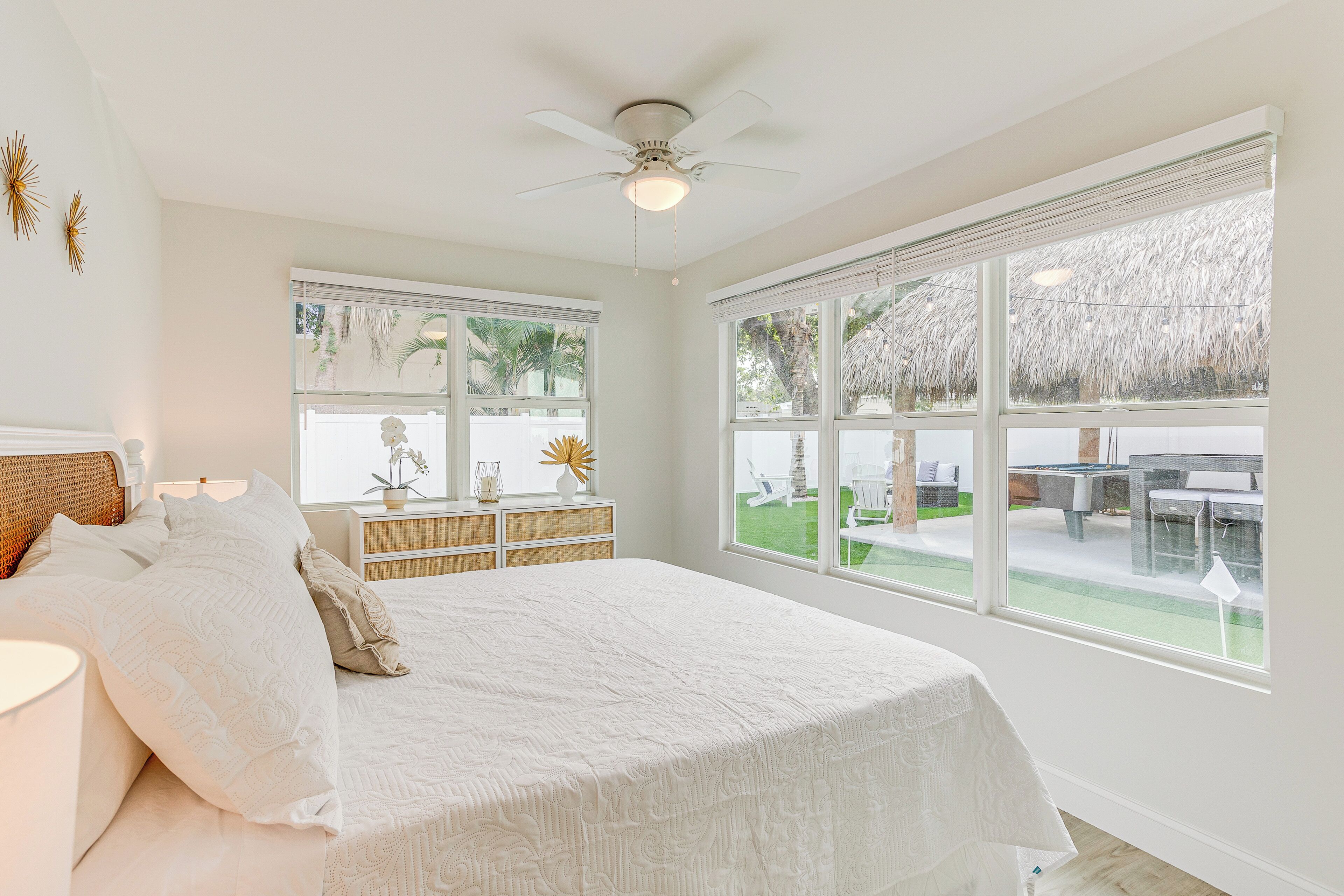 Un dormitorio con una cama grande, un ventilador de techo y vistas a un patio con mobiliario exterior.