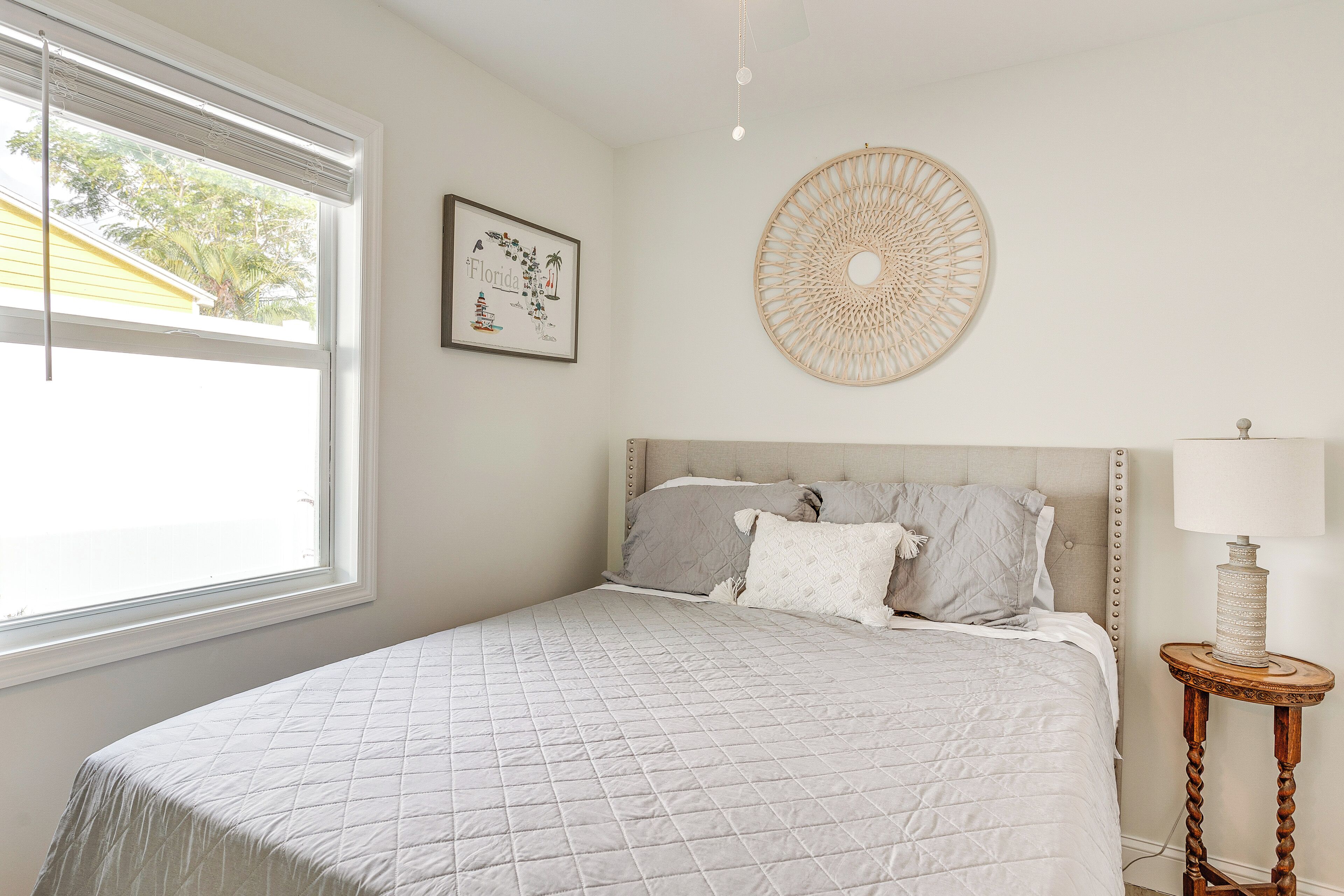 A bedroom with a large bed, a bedside lamp, a framed picture, and a decorative wall hanging.