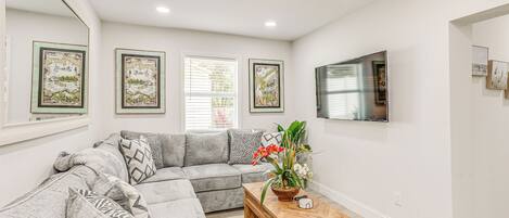 A modern living room with a sectional sofa, a coffee table, and framed artwork on the walls.