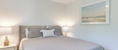Une chambre à coucher avec un lit, des tables de chevet, un ventilateur de plafond et un tableau encadré au mur.