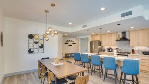 A modern kitchen with wooden cabinets, a central island, and blue bar stools. - Winter Park Condo w/ Hot Tub, Balcony & Shuttle! (Winter Park)