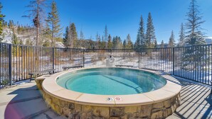 A hot tub with a stone surround, a wooden deck, and a metal fence. - Winter Park Condo w/ Hot Tub, Balcony & Shuttle! (Winter Park)