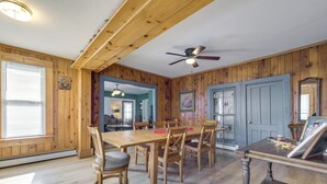 A wooden-paneled room with a dining table and chairs, a ceiling fan, and a door with a mirror. - Altmar Vacation Rental ~ 4 Mi to Salmon River! (Parish)