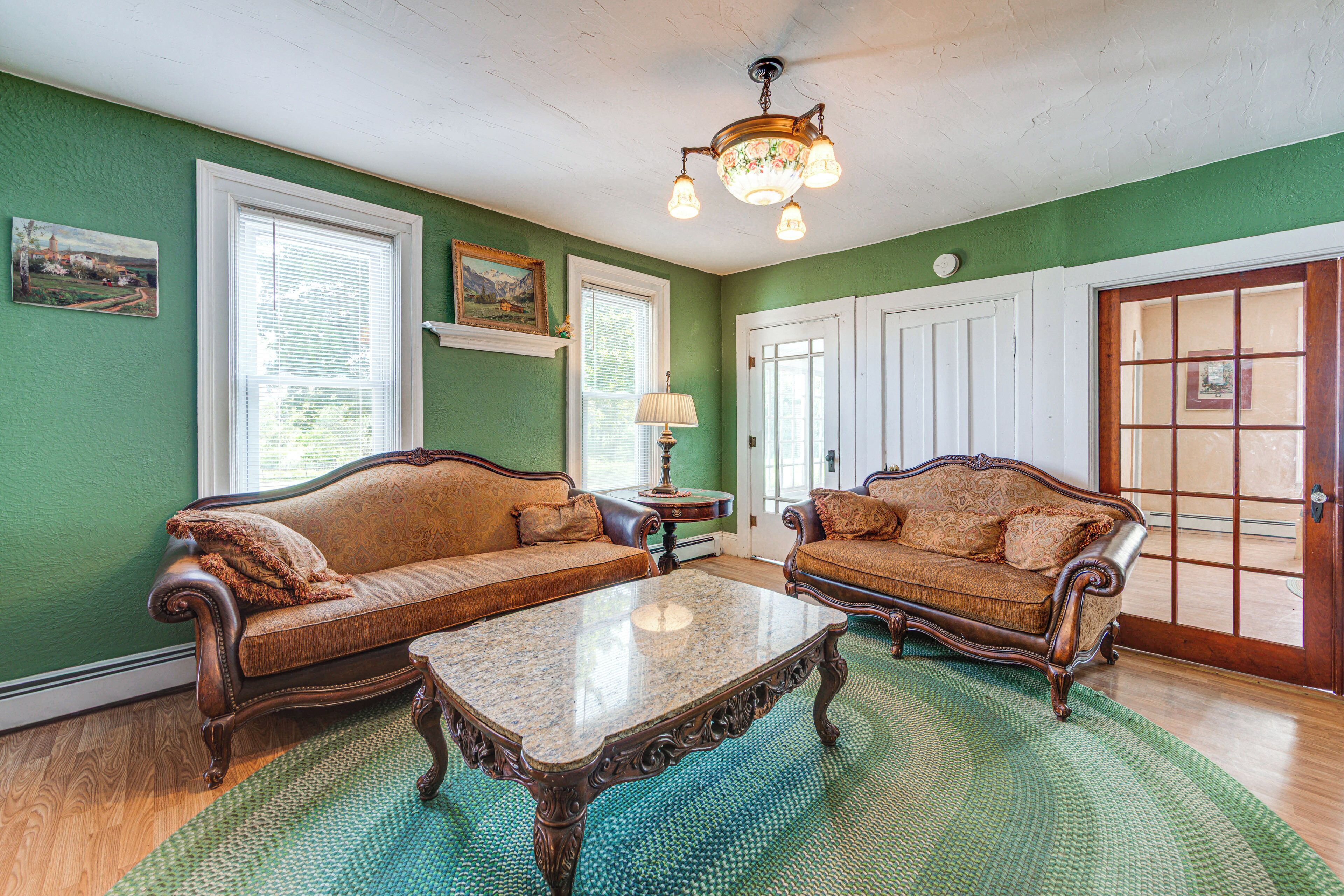 A room with two vintage-style sofas, a wooden coffee table, and a green patterned rug.