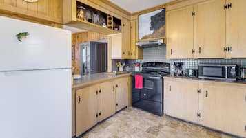A kitchen with wooden cabinets, a stainless steel refrigerator, a black oven, and a microwave.