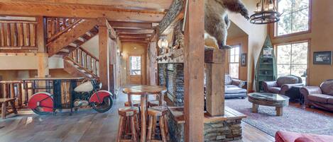 A rustic interior with a wooden staircase, a bear sculpture, a motorcycle, and leather furniture.