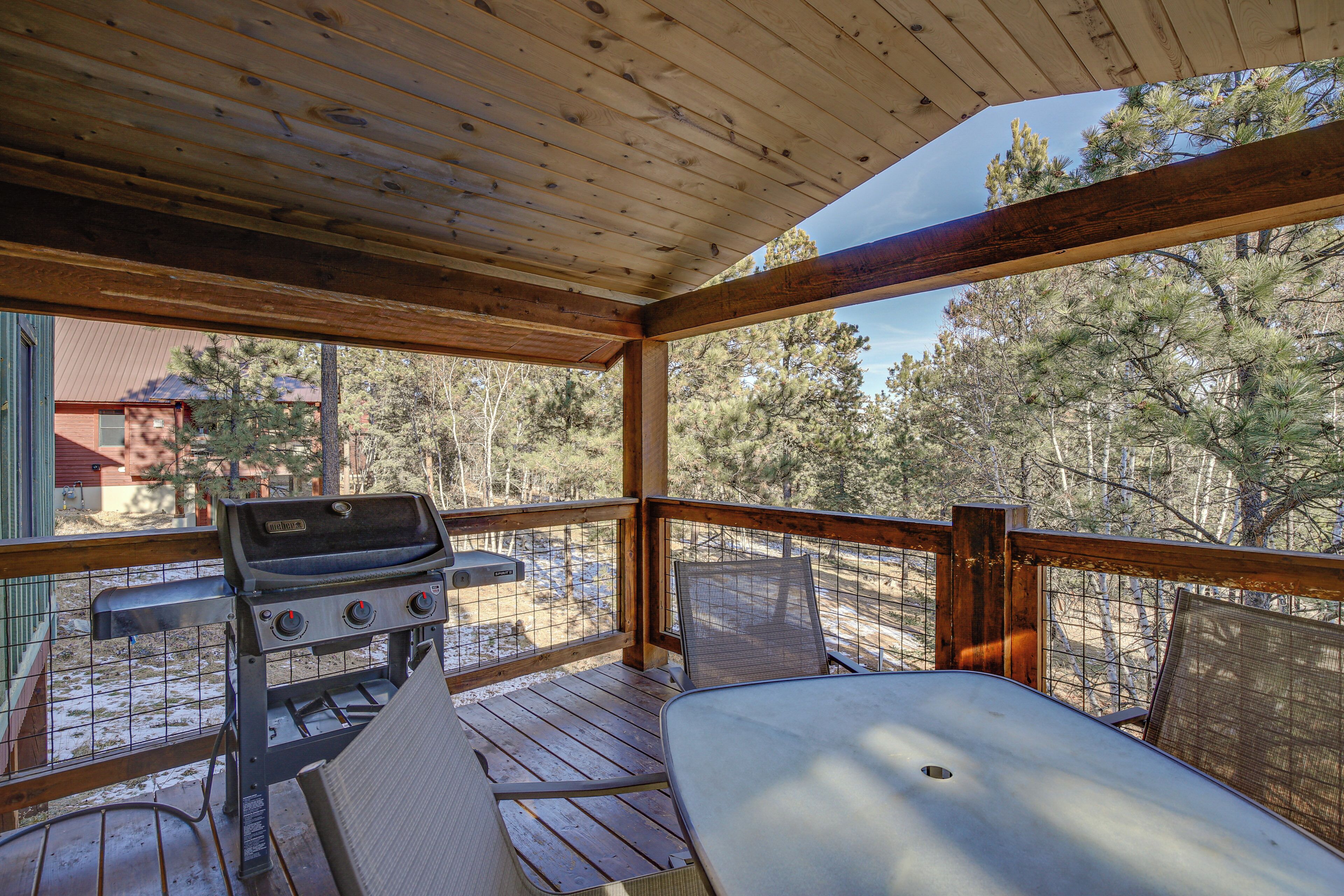 A covered outdoor area with a grill, a table, and chairs.