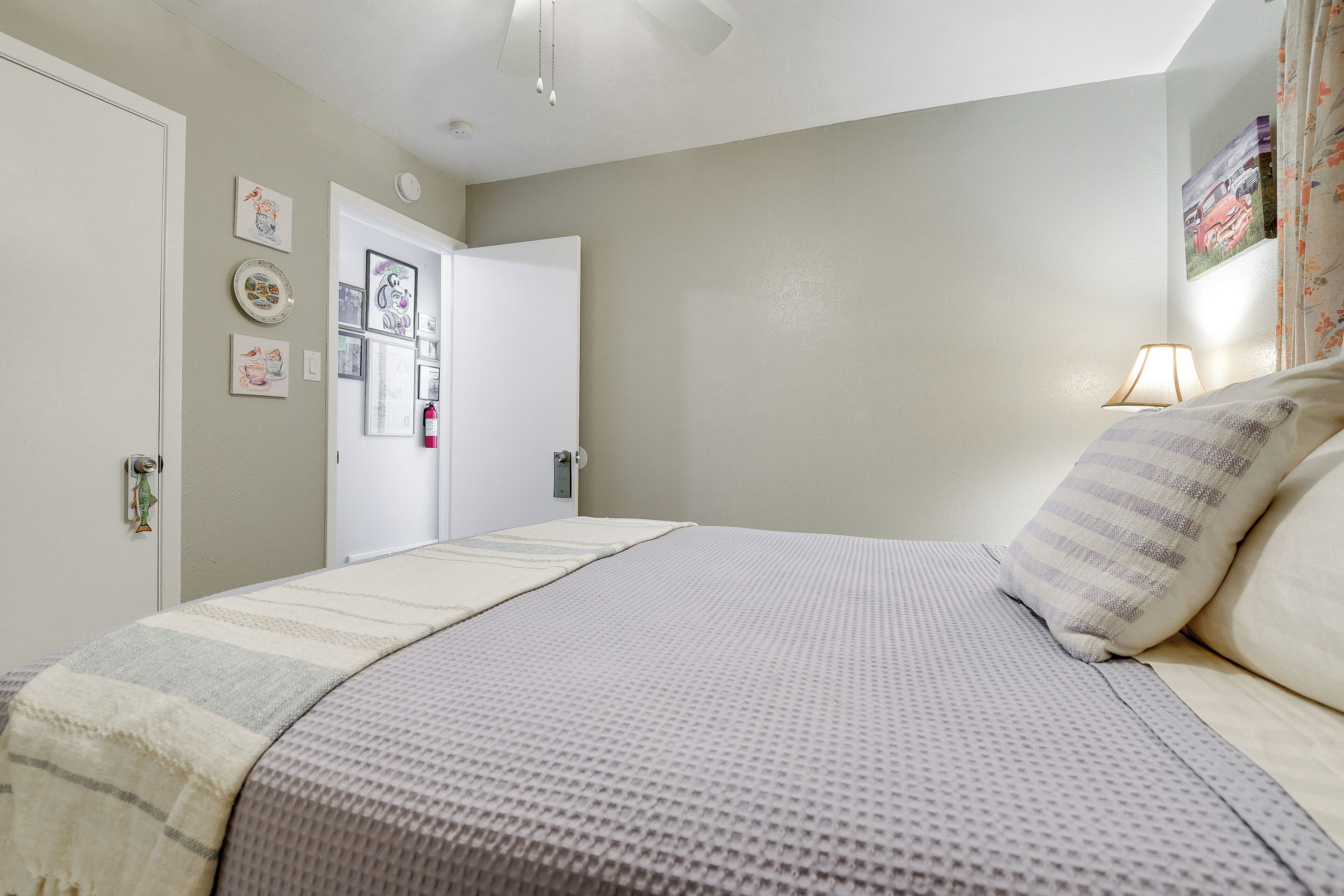 Une chambre à coucher avec un lit, une porte et un mur orné de tableaux encadrés.