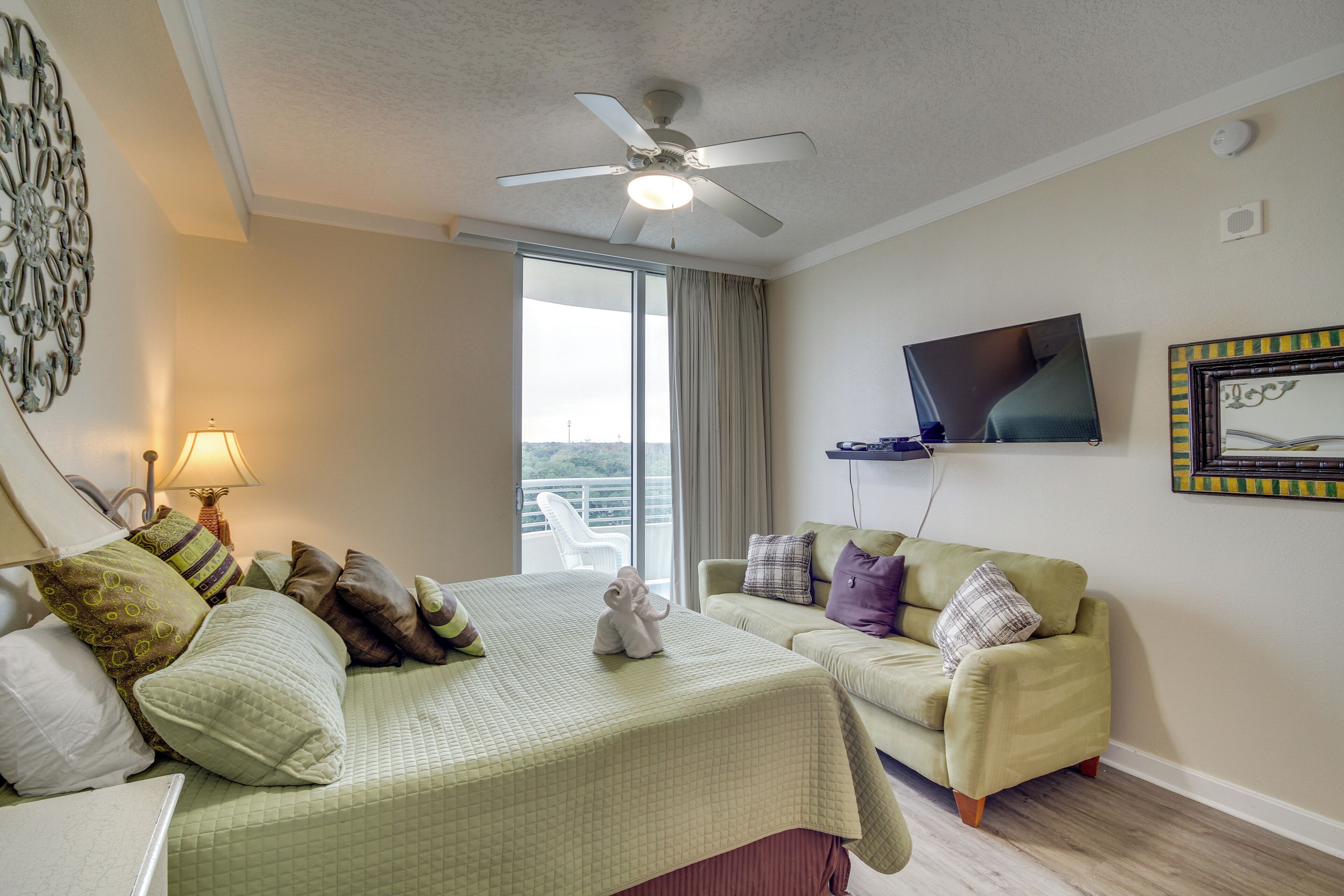A hotel room with a bed, a sofa, a television, and a window with a view.