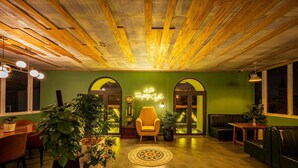 A cozy interior with a green wall, wooden ceiling beams, a neon sign, and comfortable seating areas. - Hera Boutique Hotel (Xuan Huong - Da Lat)