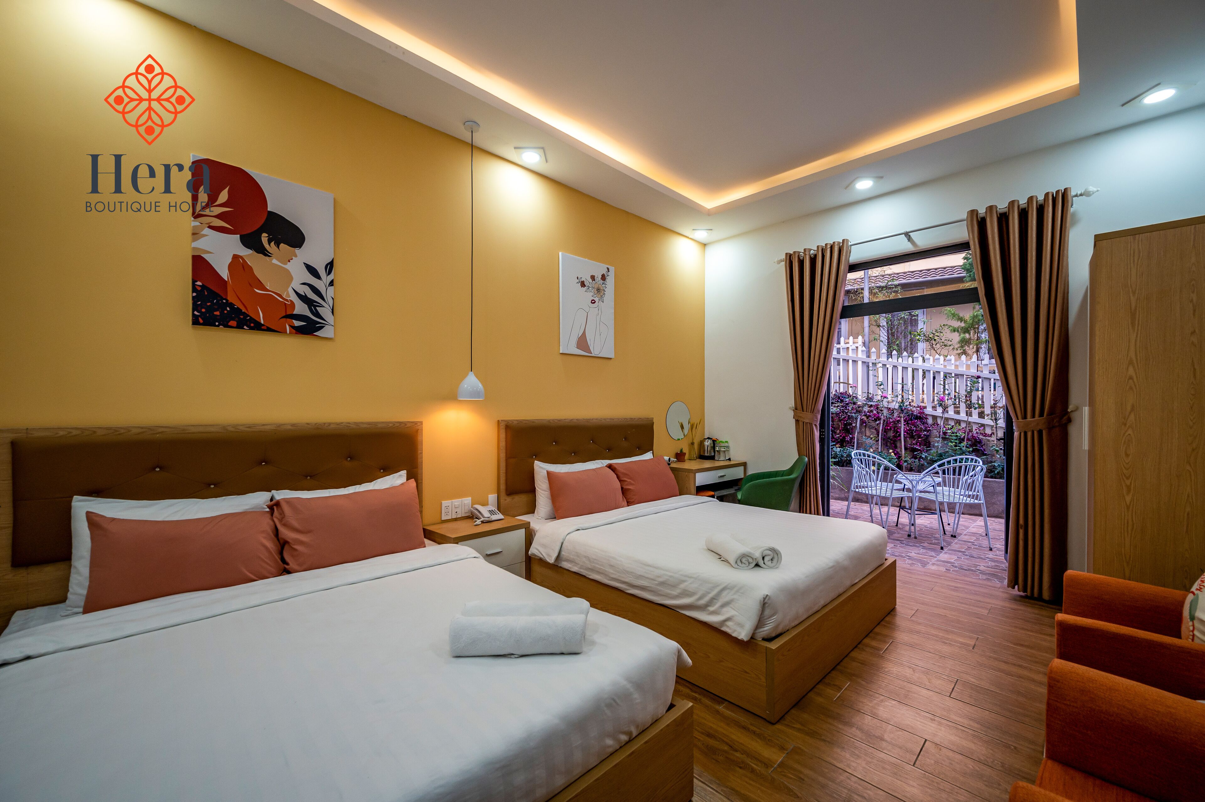 A hotel room with two beds, a desk, a chair, and a view of the outside.