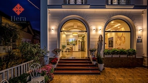 A hotel entrance with a grand archway, steps leading up to it, and potted plants on either side. - Hera Boutique Hotel (Xuan Huong - Da Lat)
