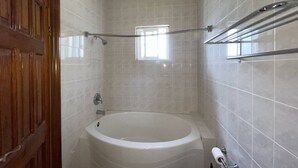 Casa de banho com banheira, chuveiro e sanita.