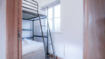 A bunk bed with a ladder, a window, and a door.