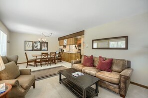 A living room with a sofa, coffee table, and dining area with chairs and a table. - C14 Gore Creek Meadows 3 Bedroom Condo by RedAwning (Vail)