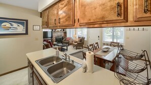 A kitchen with wooden cabinets, a double sink, and a dining area with a table and chairs.
