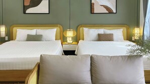 A hotel room with two beds, a sofa, and artwork on the walls. - Triland (Phu Quoc)