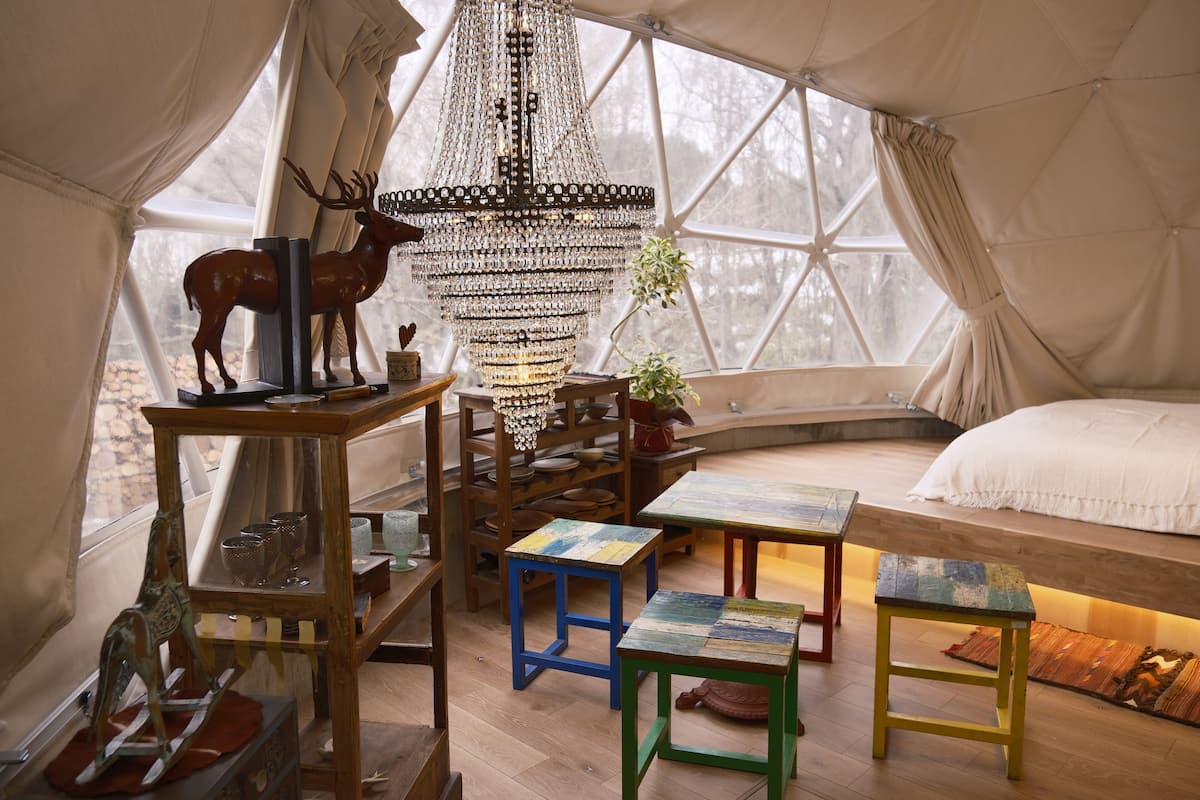 A cozy interior with a wooden bench, a chandelier, and a deer sculpture.