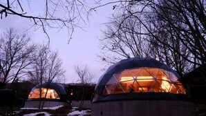 Two geodesic dome yurts with a warm interior light, surrounded by bare trees and snow on the ground. - villa Fukuza (Naganuma)
