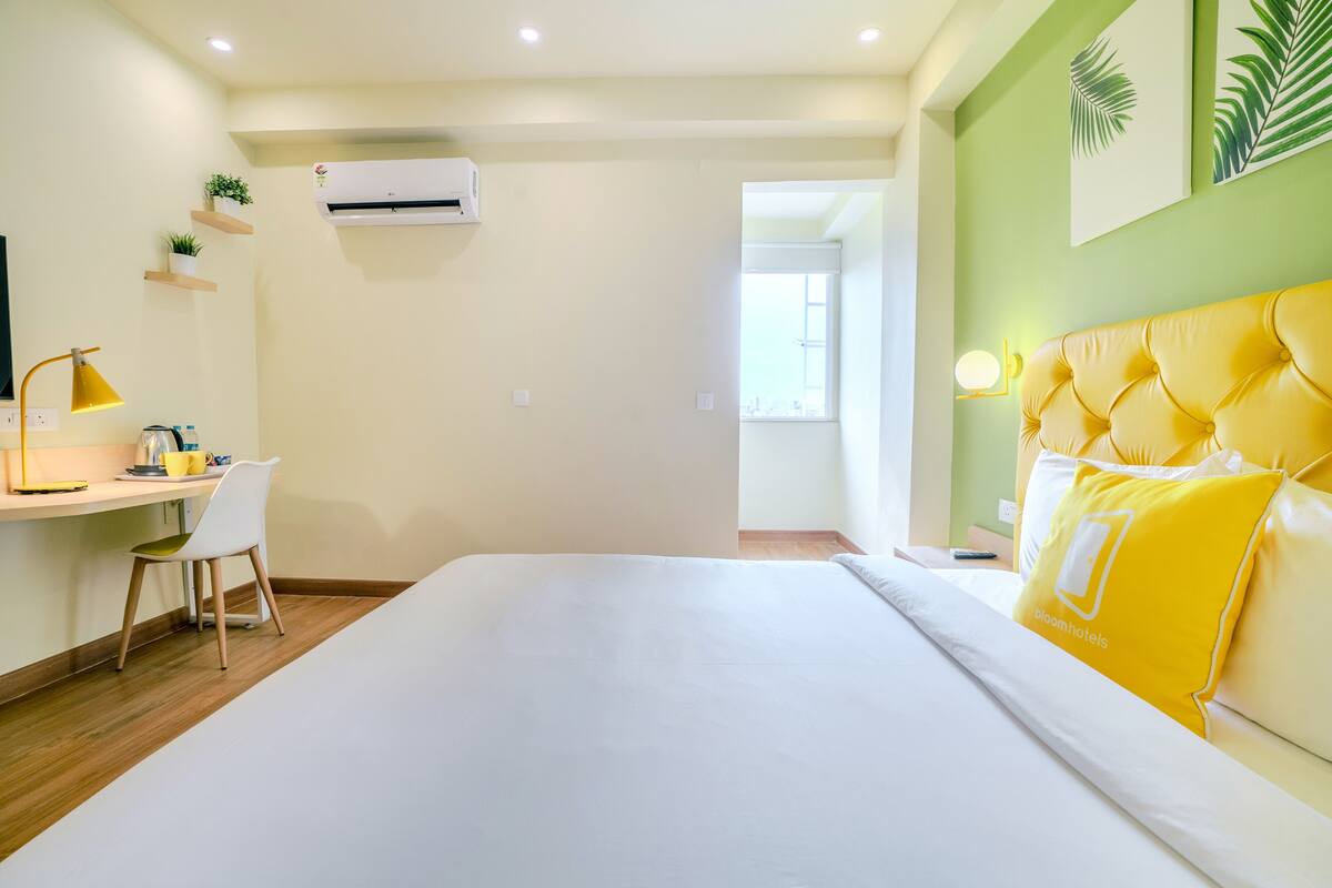 A hotel room with a bed, a desk, a chair, and a small table.