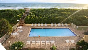 A pool area with lounge chairs and a staircase leading to a beach. - The Barefoot Getaway (Stuart)