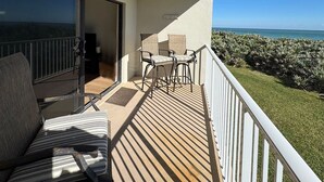 A balcony with a view of the ocean, a table with chairs, and a sofa. - The Barefoot Getaway (Stuart)