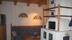 Una sala de estar acogedora con un banco de madera, una mesita y un televisor sobre un mueble.