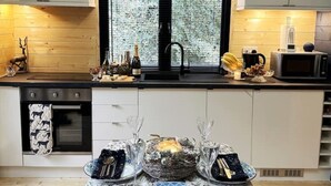 Eine moderne Küche mit schwarzem Arbeitsplatz, einer Spüle und einem Fenster mit Milchglas. Auf der Arbeitsfläche stehen Weinflaschen, eine Mikrowelle und ein Toaster.