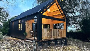 Eine Holzhütte mit einer Holzterrasse, einer Veranda und einem großen Fenster.