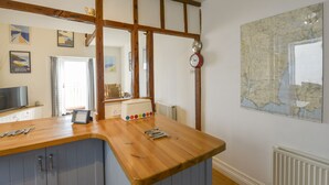 Una cocina con vigas de madera, un mapa en la pared y un reloj.