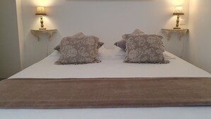 A neatly made bed with two pillows and a brown throw blanket. There are two wall-mounted lamps on either side of the bed. - Au Coeur de Sarlat, L'appart d'à Coté...1 Chambre (Sarlat-la-Canéda)