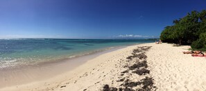 A beach with clear turquoise water, sandy shore, and a few people relaxing.