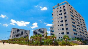 Un hotel moderno con varios pisos, techo plano y ubicación frente a la playa.
