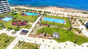 Un resort con múltiples piscinas, una zona de playa y vista al océano.