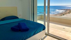 Un dormitorio con cama, vista al océano y balcón.
