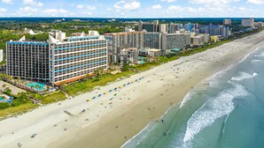 A beachfront hotel with multiple buildings, a sandy beach, and a clear view of the ocean. - Amazing Direct Modern 2nd Floor Oceanfront w Fireplace (Myrtle Beach)