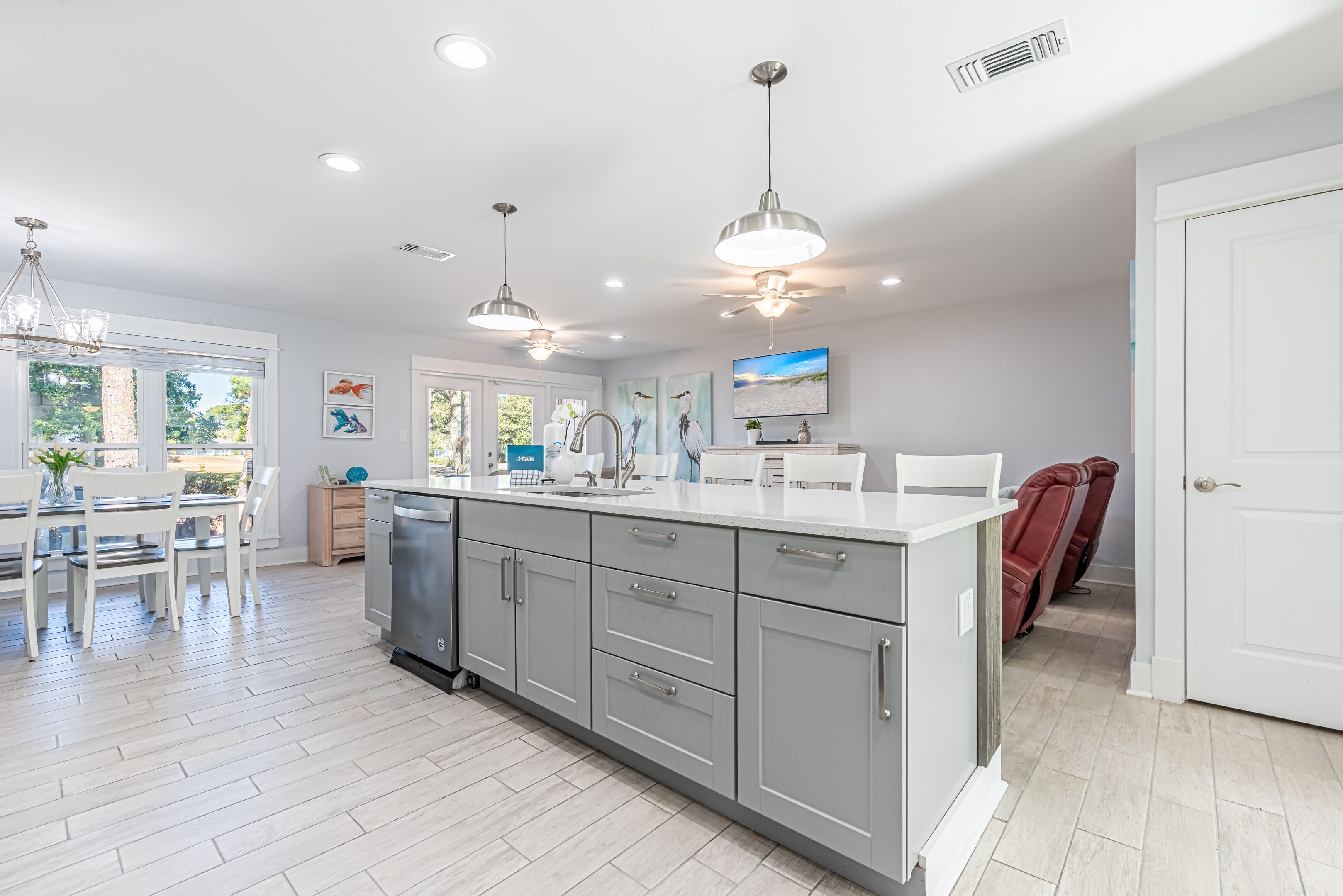 A modern kitchen with grey cabinets, a white countertop, and pendant lighting.