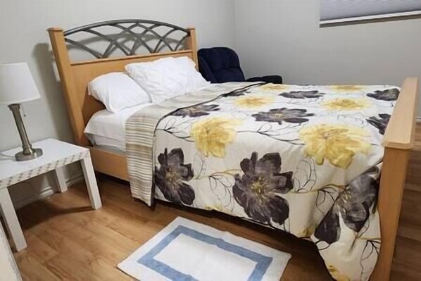 Une chambre à coucher avec un lit, une table de chevet, une chaise et une fenêtre.