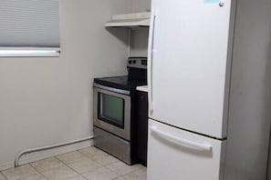 Une cuisine de taille réduite, dotée d’un four encastré et d’un réfrigérateur blanc.