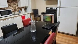 A compact kitchen with white cabinets, a microwave, a stove, and a refrigerator. - Chesskings Guest House - Unit 2 Notredame Avenue (Winnipeg)