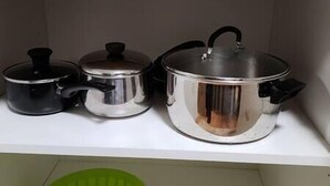 A kitchen shelf with three stainless steel pots and a black pot. - Chesskings Guest House - Unit 2 Notredame Avenue (Winnipeg)