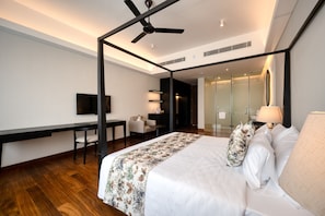 A modern hotel room with a bed, a desk, a chair, a television, and a ceiling fan. - Taprobane House (Colombo)